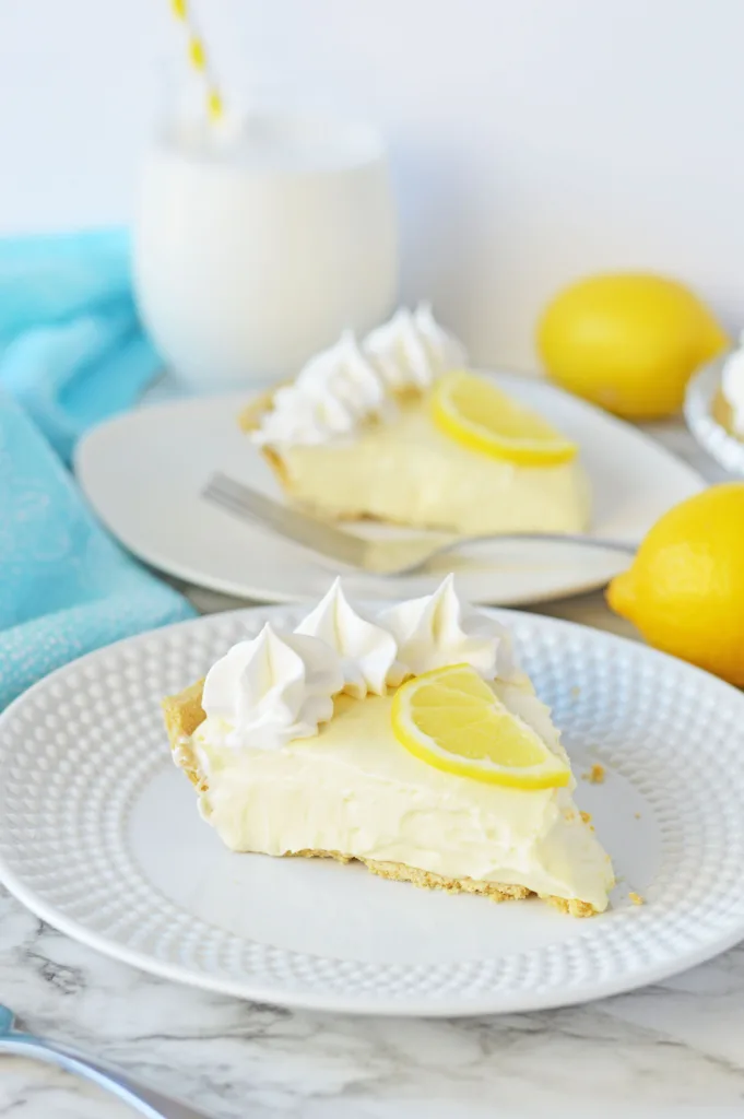 slices of No Bake Lemon Cheesecake Pie on plates topped with a fresh lemon slice
